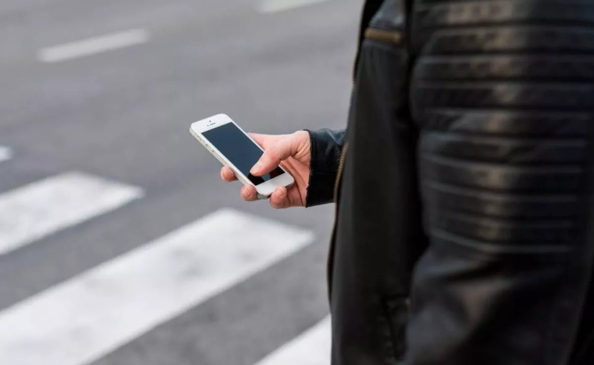 Peatón cruzando la calle con un móvil. /Freepik