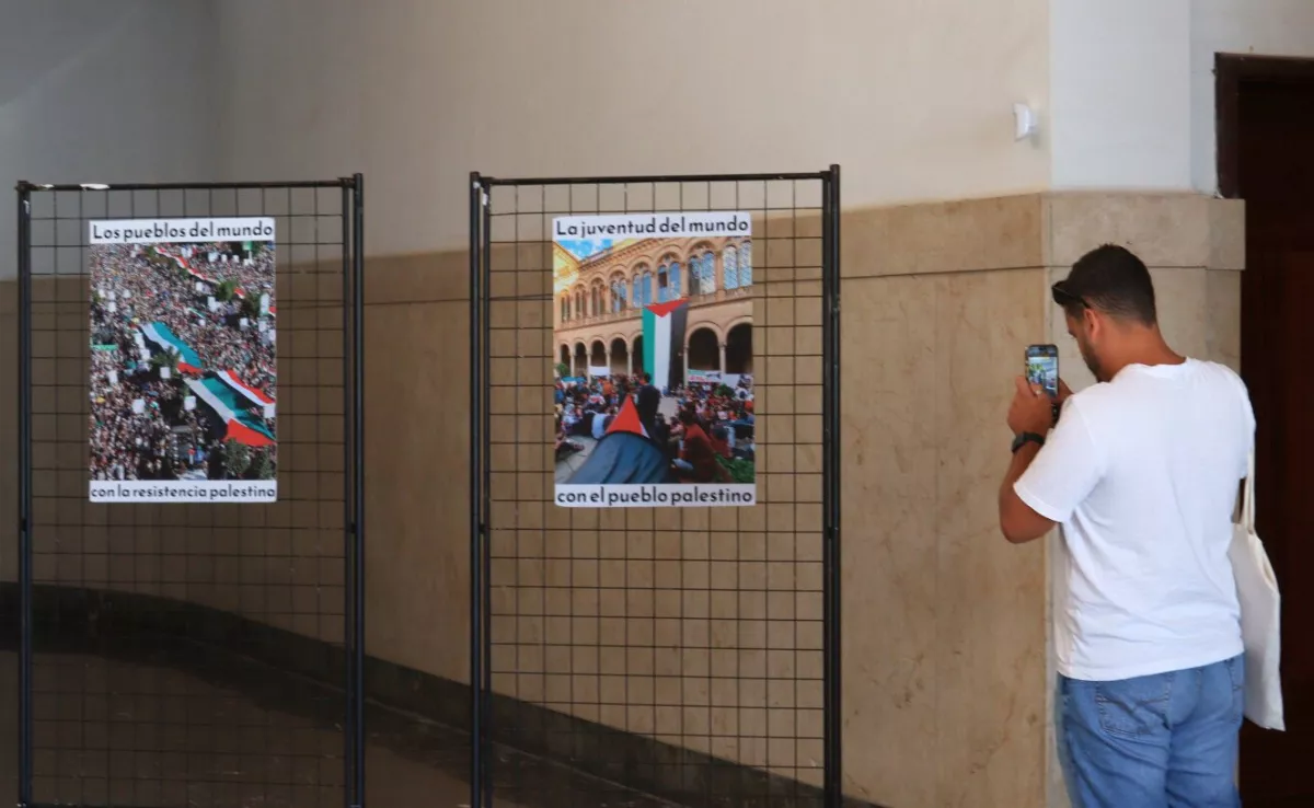 Un estudiante captura con su móvil uno de los carteles de la exposición que muestra el horror en Gaza. / ATLÁNTICO HOY 