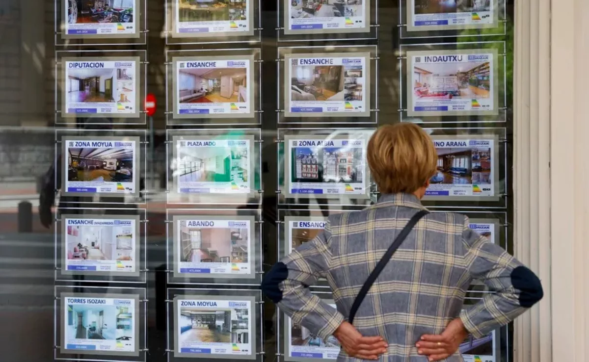 Una mujer enfrente de una inmobiliaria consultando el precio de las viviendas / EFE