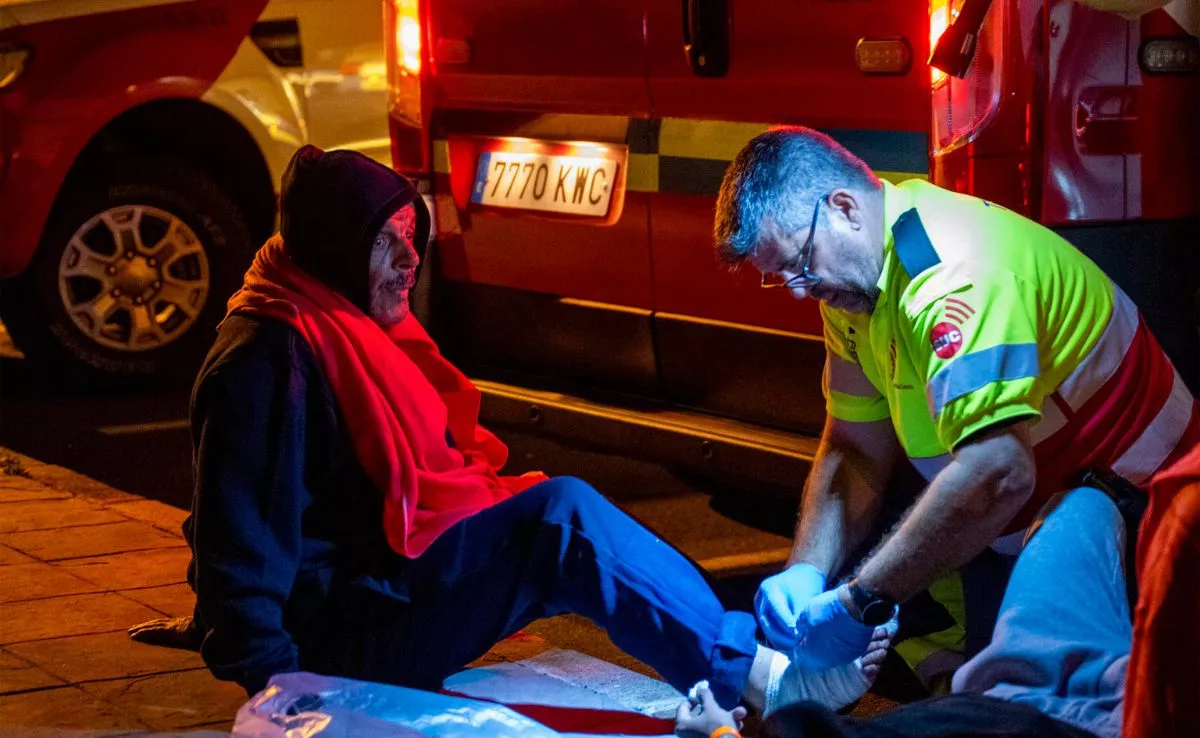 Un sanitario del SUC atiende a uno de los 24 hombres de origen magrebí que llegaron en partera por sus propios medios a Lanzarote. /EFE /Adriel Perdomo