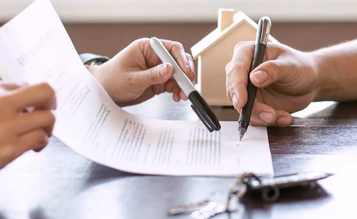 Dos personas firmando un contrato de compraventa.  / AH