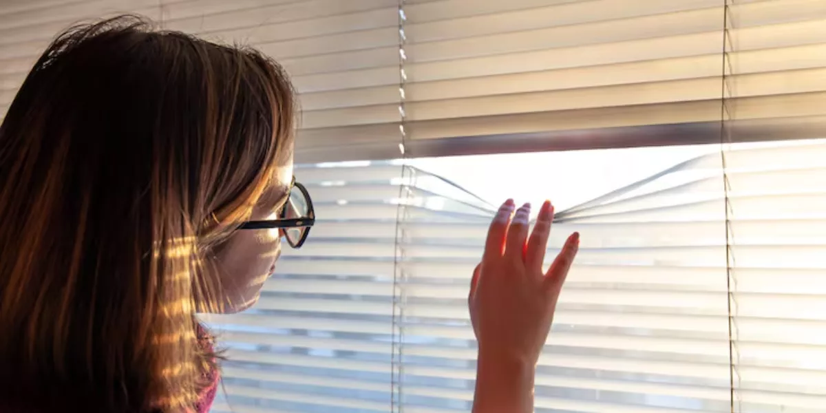 Imagen de una persona detrás de una persiana / PEXELS 