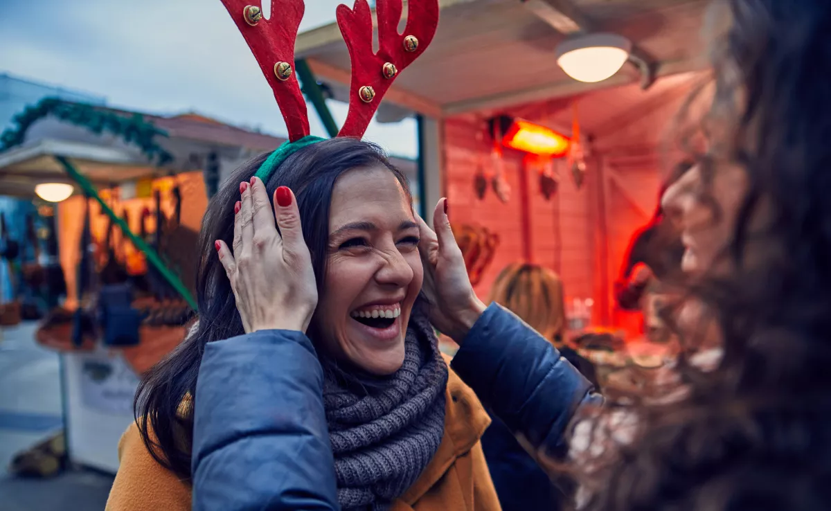 Imagen de unas personas disfrutando de un mercadillo navideño / CANVA