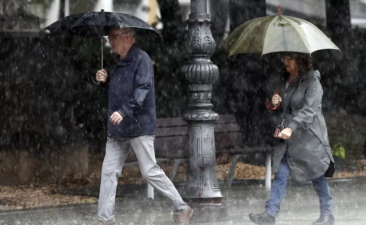 Imagen de archivo de dos personas bajo la lluvia / EFE - JESÚS DIGES