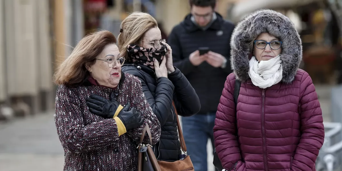 Imagen de tres personas en la calle con frío / EFE