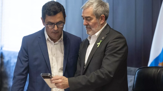 Fernando Clavijo, presidente de Canarias, muestra la pantalla de su móvil a Pablo Rodríguez, consejero de Obras Públicas, Vivienda y Movilidad del Ejecutivo regional. / MIGUEL BARRETO-EFE