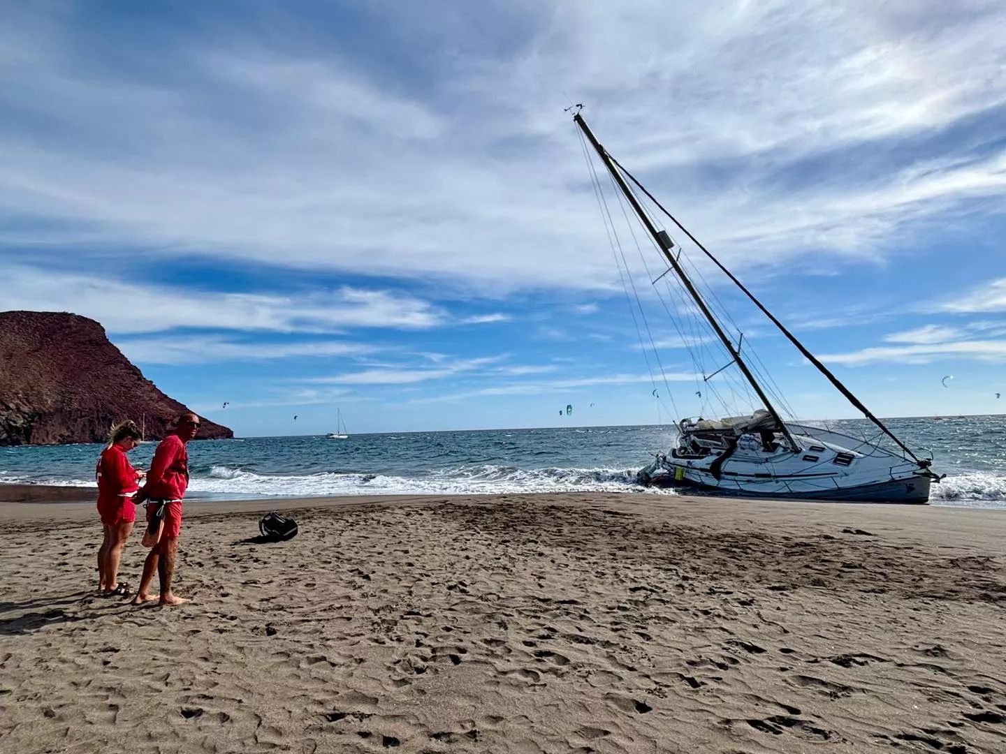 Dos socorristas observan el velero 'Cora La Gomera', embarrancado en la playa de La Tejita./ REDES Dos socorristas observan el velero 'Cora La Gomera', embarrancado en la playa de La Tejita./ REDES