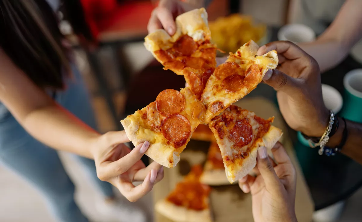 Imagen de un grupo de personas comiéndose una pizza / CANVA