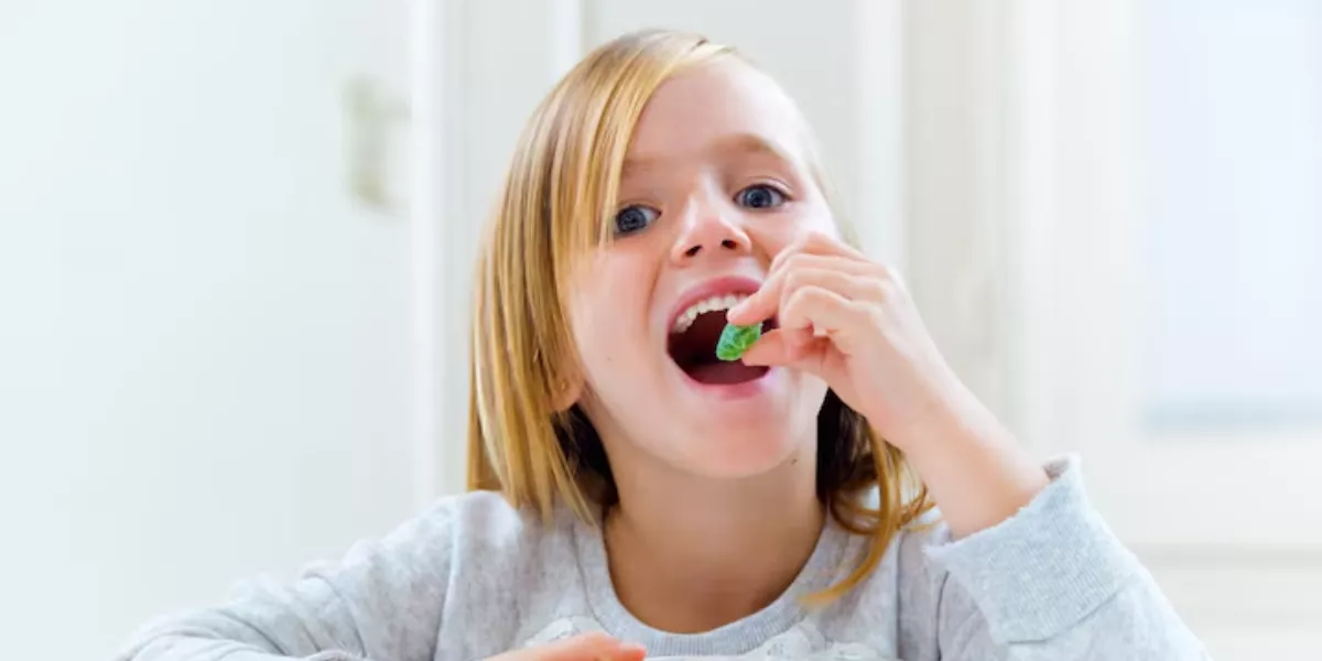 Imagen de una niña comiendo gominolas / FREEPIK