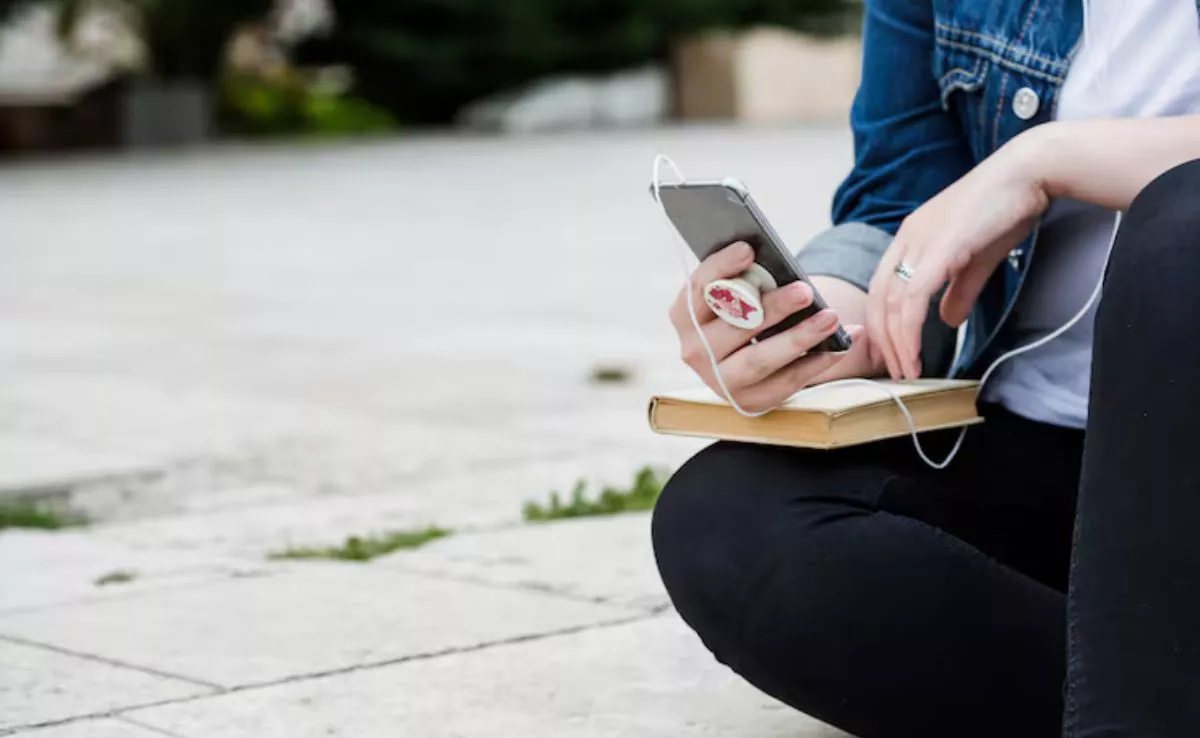 Una mujer sentada mira su móvil. /Freepik