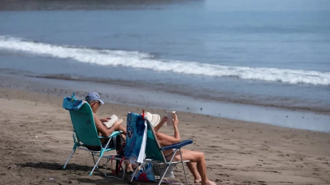 Dos turistas en la playa de Gran Tarajal (Fuerteventura) / EFE - CARLOS DE SÁA