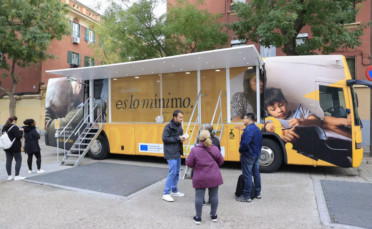 Imagen de unas personas frente a la guagua informativa sobre el Ingreso Mínimo Vital / EFE Imagen de unas personas frente a la guagua informativa sobre el Ingreso Mínimo Vital / EFE