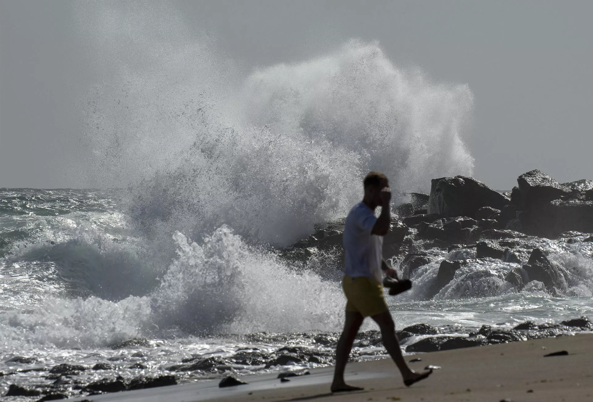 Fuerte oleaje provocado por la borrasca Therese en el litoral de Costa Teguise (Lanzarote). En la imagen un turista pasea por Playa Bastián. EFE/Adriel Perdomo