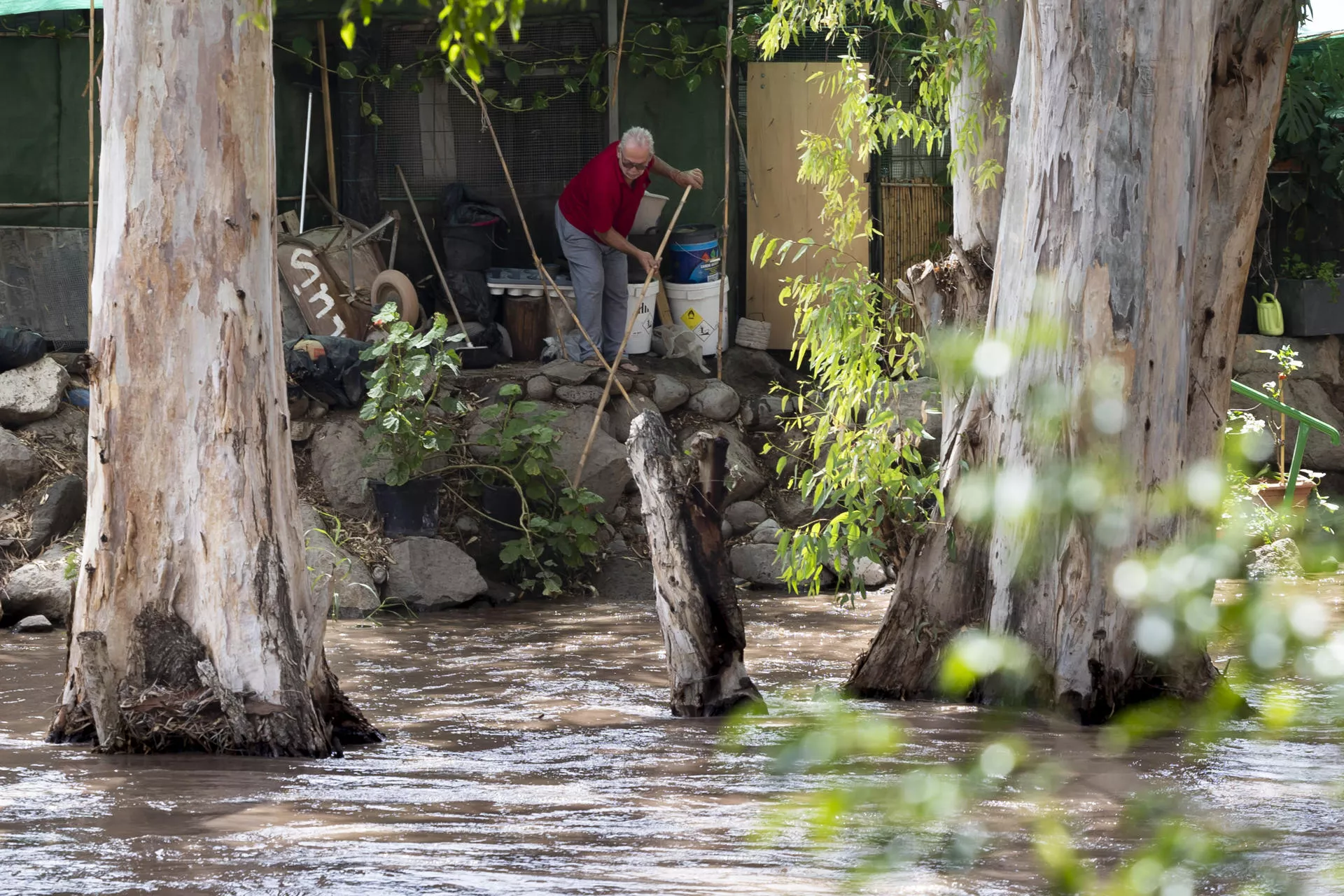 Un vecino del barranco de Arguineguín trata de proteger su vivienda ante la crecida del caudal del barranco./ EFE
