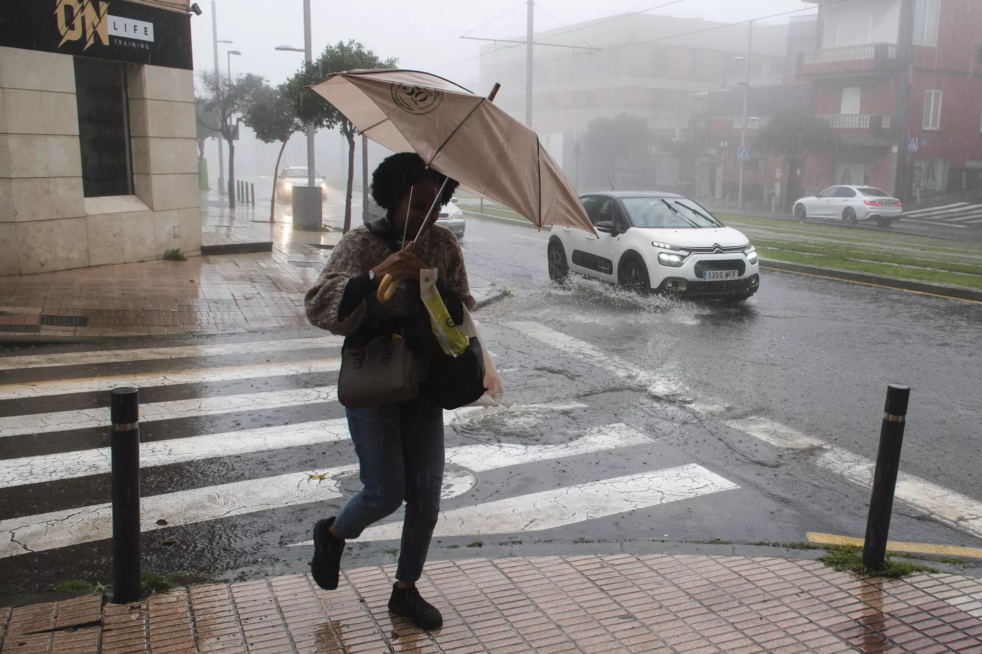 Una persona se refugia de la lluvia con paraguas este martes en el municipio tinerfeño de La Laguna. / EFE - ALBERTO VALDÉS