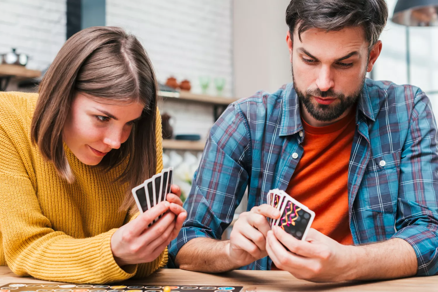Una pareja joven juega a las cartas en su casa / FREEPIK