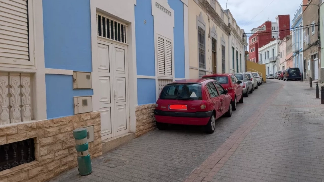 Los coches aprovechan la caída o la ausencia de bolardos para aparcar delante de las casas, bloqueando las ventanas de los bajos de los edificios. / AH