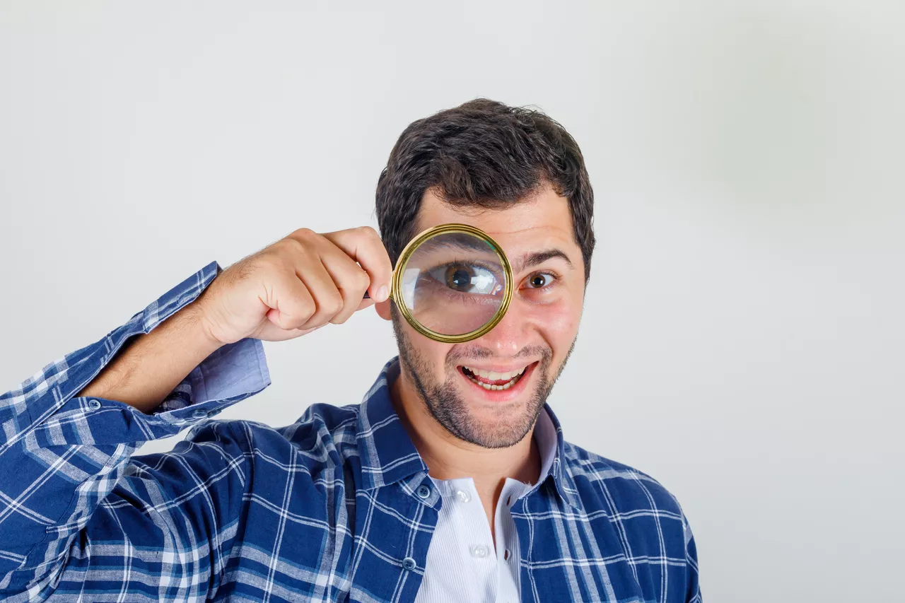 Hombre mira a través de una lupa / FREEPIK