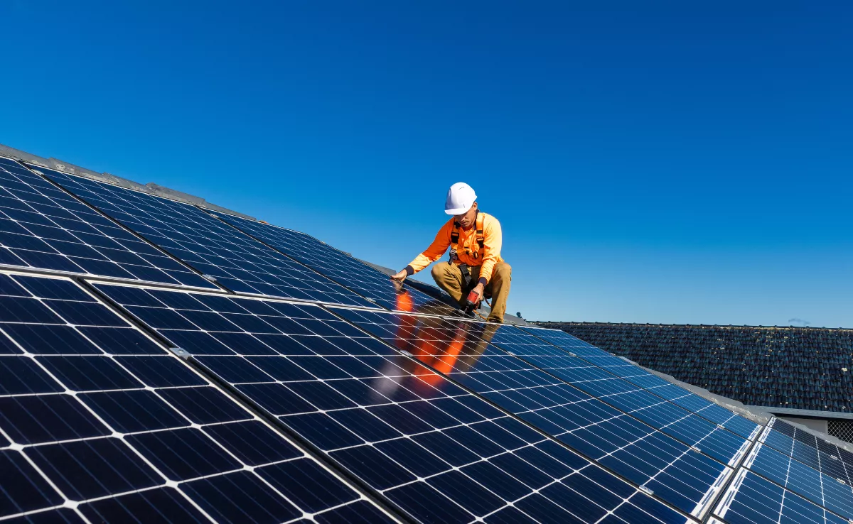 Imagen de una persona instalando placas solares / CANVA