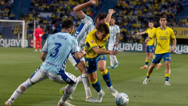 El defensa del Málaga Carlos Puga (i) disputa un balón con el delantero de Las Palmas Manu Fuster (d) / QUIQUE CURBELO - EFE El defensa del Málaga Carlos Puga (i) disputa un balón con el delantero de Las Palmas Manu Fuster (d) / QUIQUE CURBELO - EFE