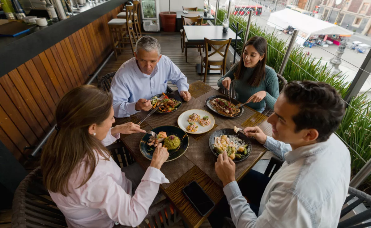 Imagen de un grupo de personas comiendo en un restaurante / CANVA