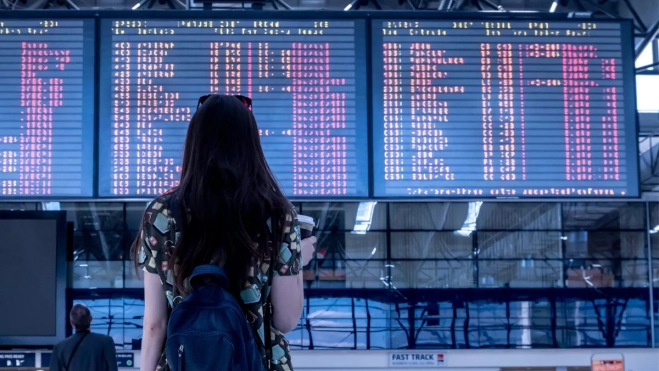 Imagen de una chica mirando los horarios de los aviones en un aeropuerto / CANVA Imagen de una chica mirando los horarios de los aviones en un aeropuerto / CANVA