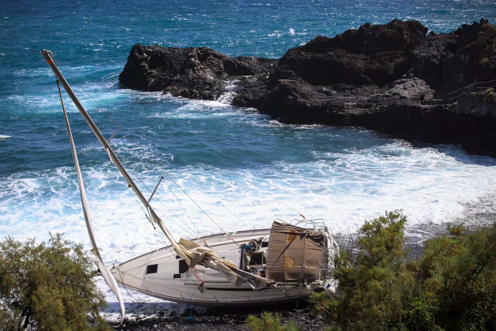 Un velero permanece encallado desde la tarde del lunes en la playa de Los Guinchos, en el municipio palmero de Breña Baja. / LUIS G MORERA-EFE