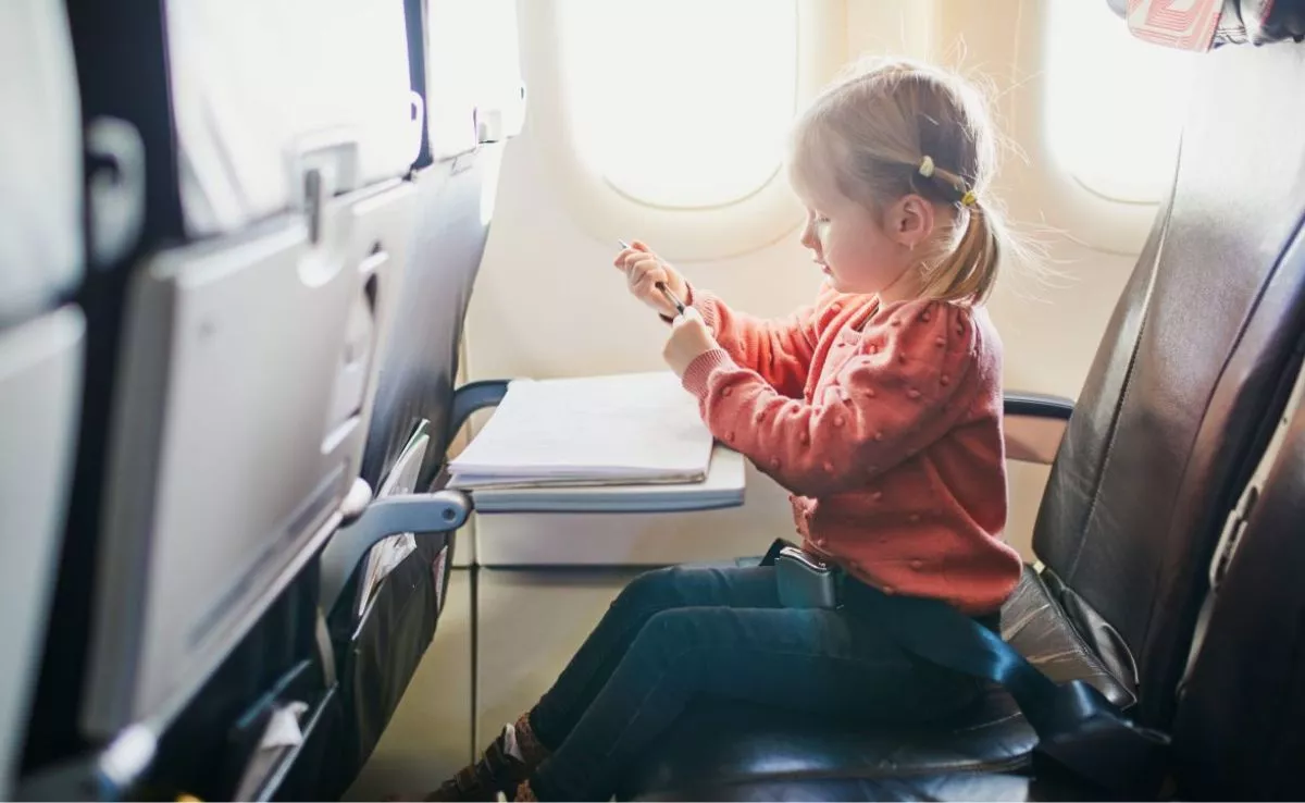 Una niña se entretiene dibujando en un avión | Foto de 123RF/epokrovsky