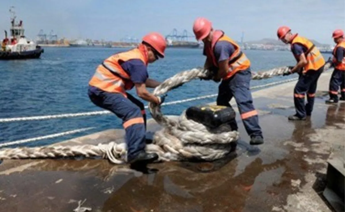 Dos trabajadores amarran el cabo de un buque al noray. / SEPCAN