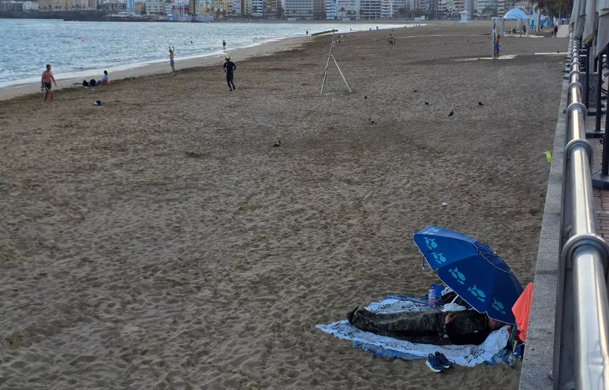 Una persona sin hogar pernoctando en la playa de Las Canteras este martes. AH