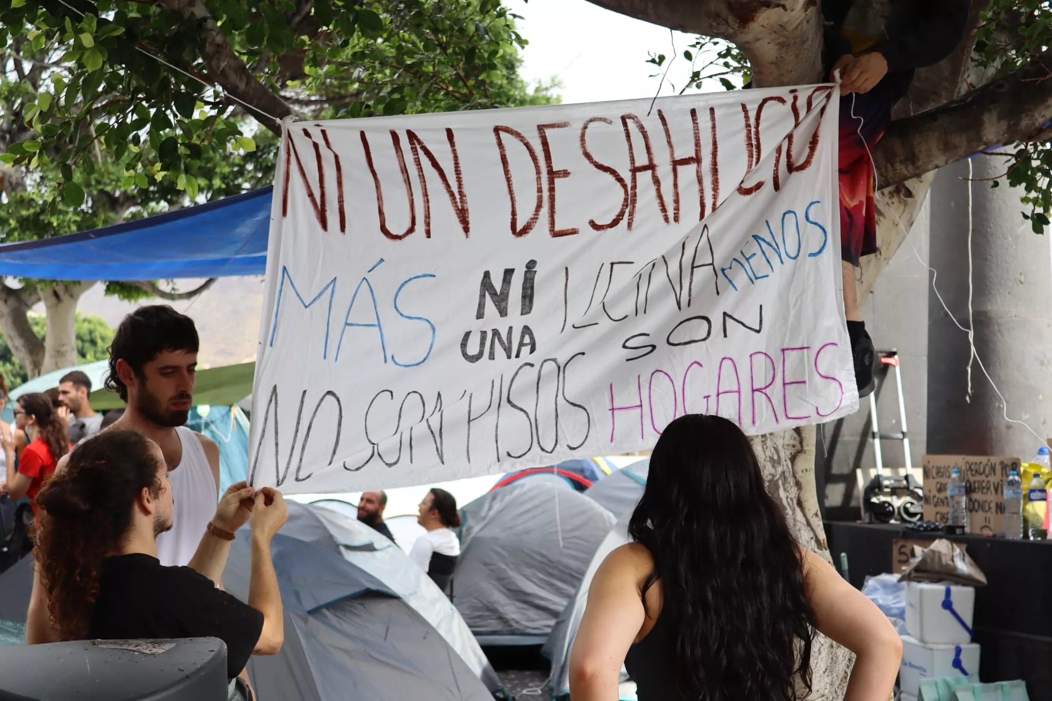 Un grupo de personas en la acampada por la vivienda en Tenerife colocan una pancarta. / AH