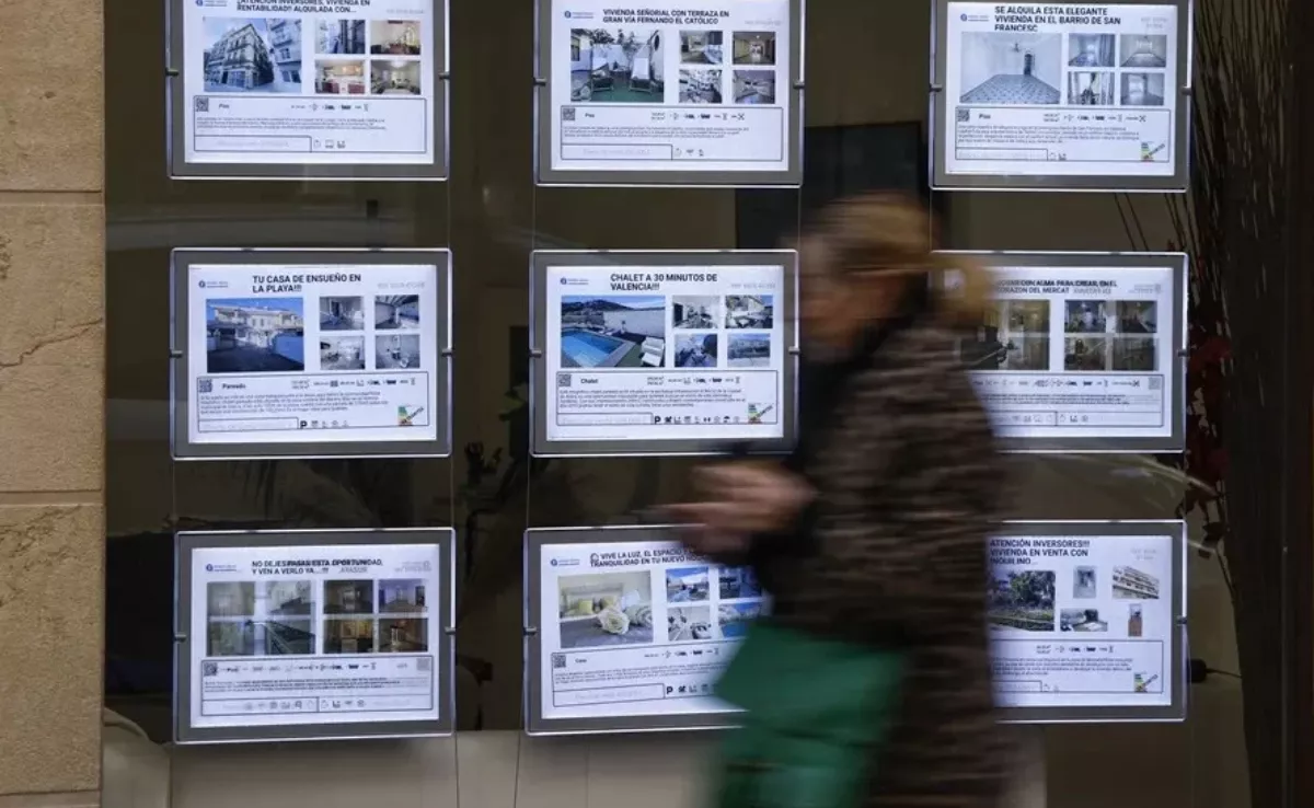 Una mujer pasa delante de una inmobiliaria / EFE