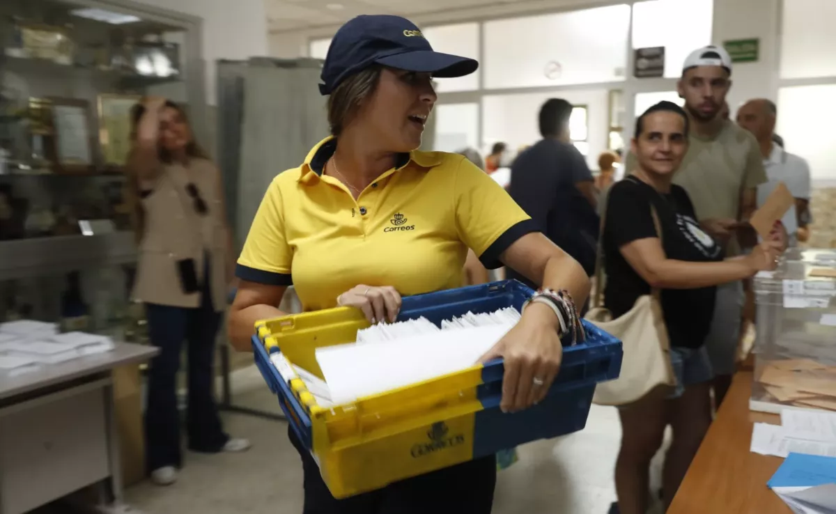 Una cartera porta una caja con votos por correo para entregar en un colegio electoral / EFE