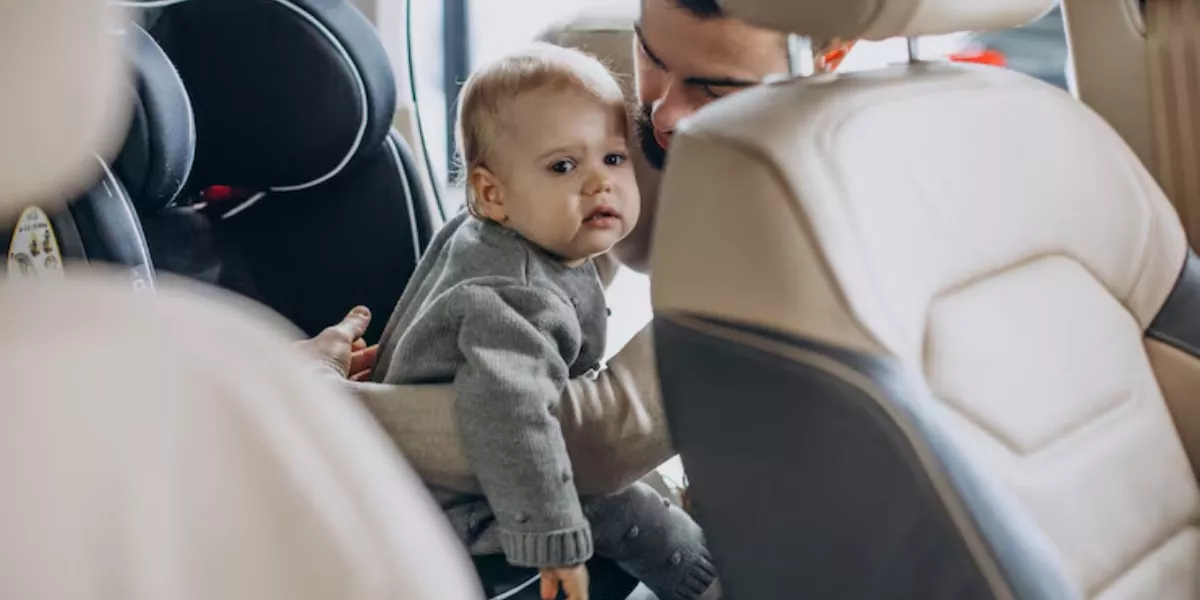 Imagen de un padre colocando a su bebé en la silla del coche / FREEPIK
