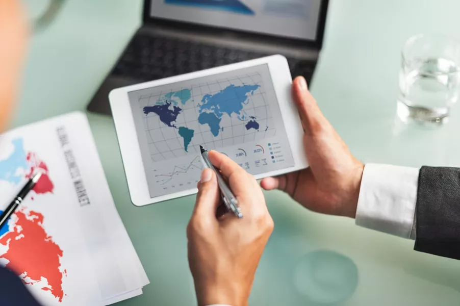 Profesional analizando datos y estadísticas internacionales en una tableta digital.