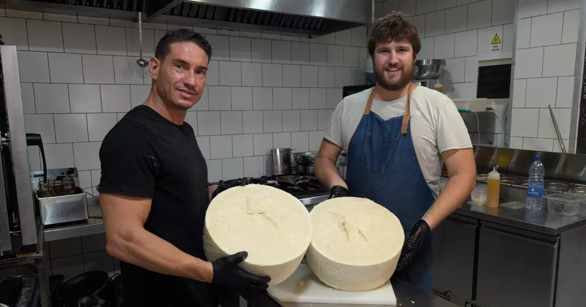 Riccardo Beretta, en la cocina de La Rotisería Italiana, tras cortar un queso de oveja de 30 kilos. / M. REYES 