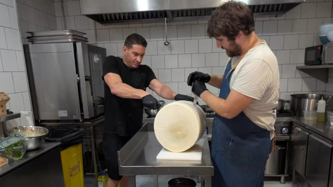 Beretta, a la derecha, abre la enorme pieza de queso con un cuchillo y la ayuda de un compañero. / M. REYES Beretta, a la derecha, abre la enorme pieza de queso con un cuchillo y la ayuda de un compañero. / M. REYES